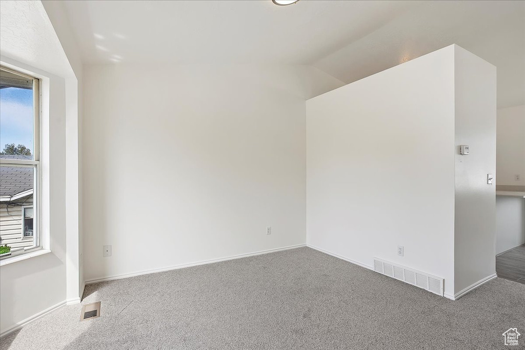 Carpeted empty room with visible vents and baseboards