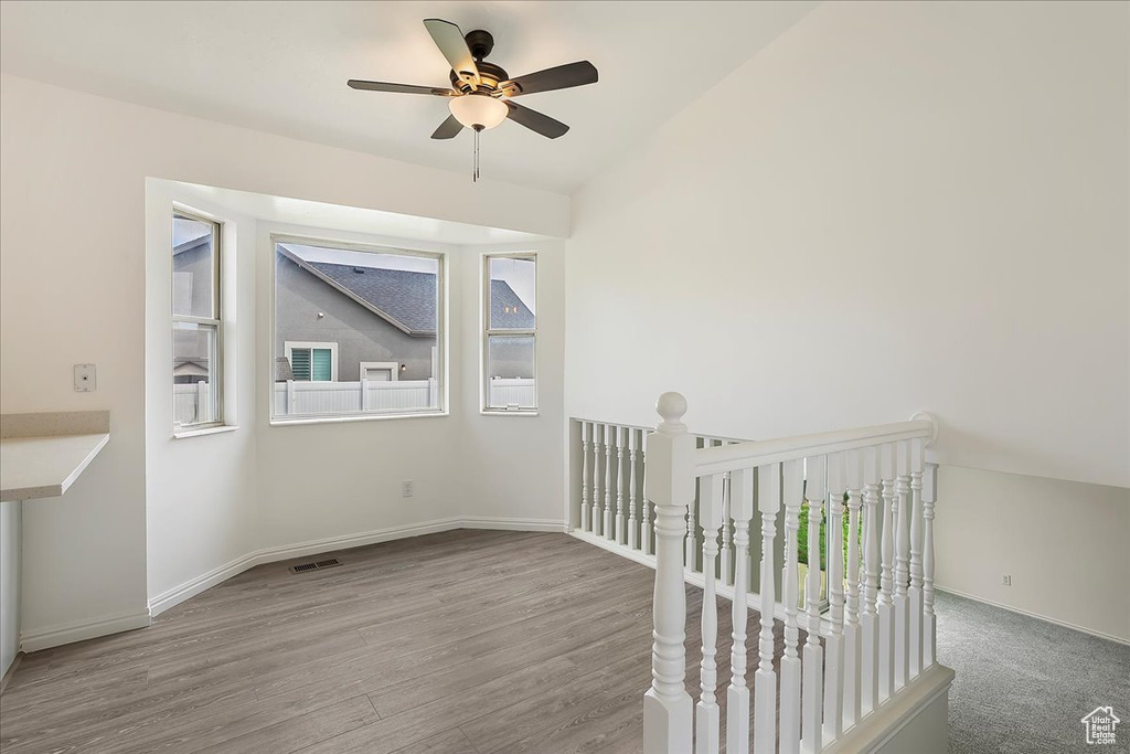 Spare room featuring visible vents, ceiling fan, baseboards, vaulted ceiling, and wood finished floors