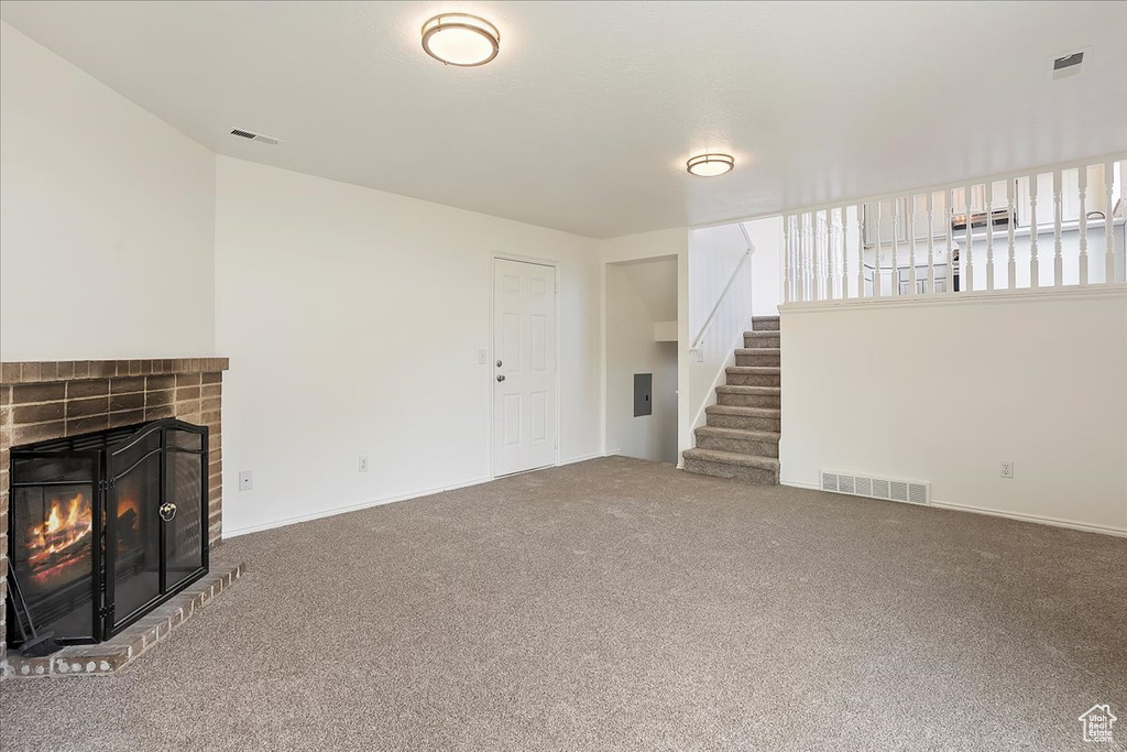 Unfurnished living room with visible vents, a fireplace, carpet floors, and stairway