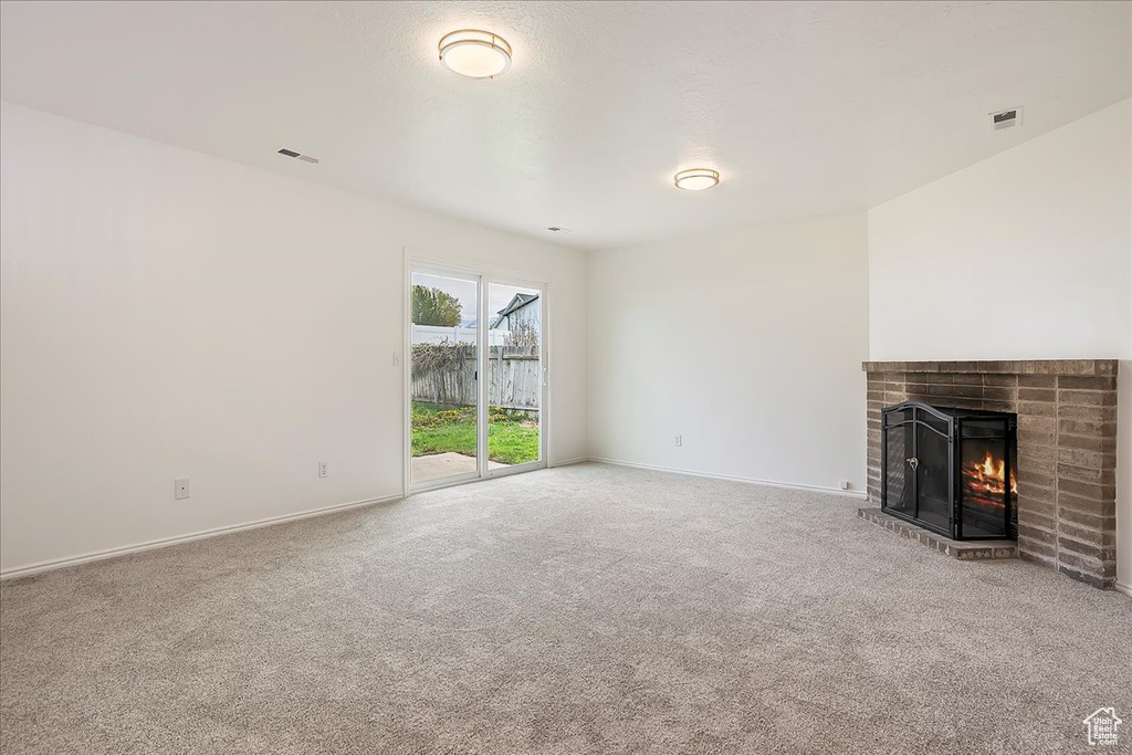 Unfurnished living room featuring visible vents, baseboards, carpet floors, and a fireplace
