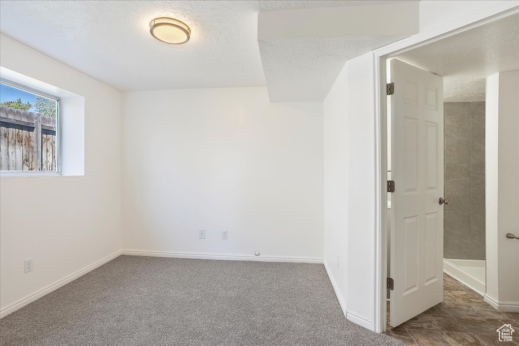 Carpeted empty room with a textured ceiling and baseboards