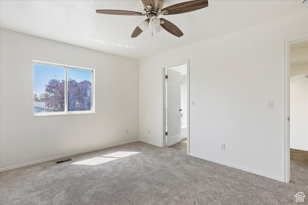 Carpeted spare room with baseboards, visible vents, and ceiling fan