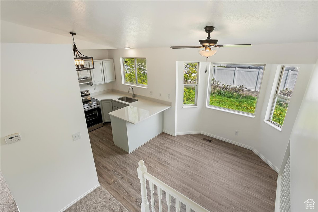 Kitchen with a sink, light countertops, baseboards, stainless steel electric range, and a peninsula