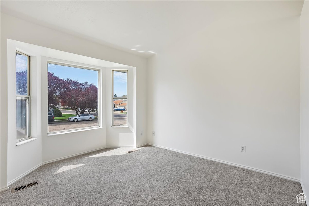 Carpeted empty room with visible vents and baseboards