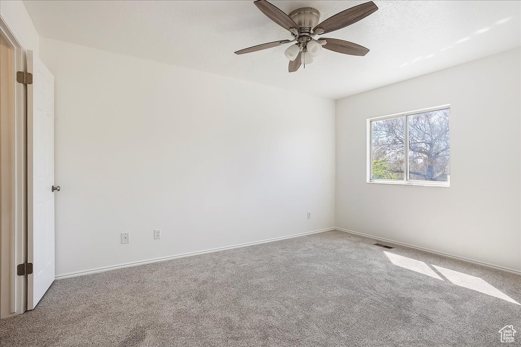 Empty room featuring ceiling fan, baseboards, carpet, and visible vents