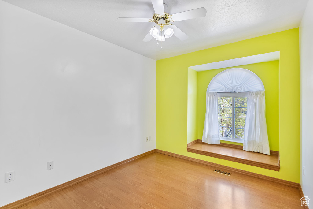 Spare room featuring baseboards, visible vents, wood finished floors, and a ceiling fan