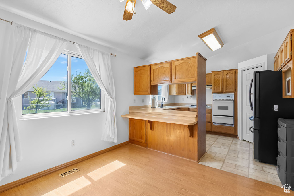 Kitchen with white oven, a warming drawer, light countertops, a ceiling fan, and a peninsula
