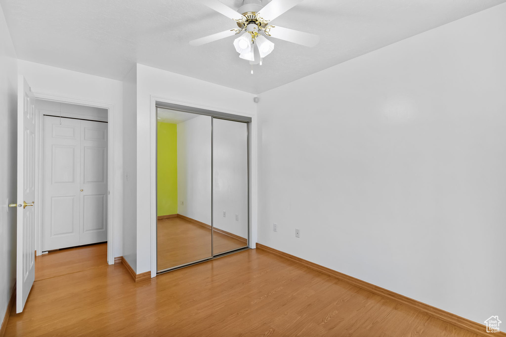 Unfurnished bedroom with baseboards, light wood-type flooring, a ceiling fan, and a closet