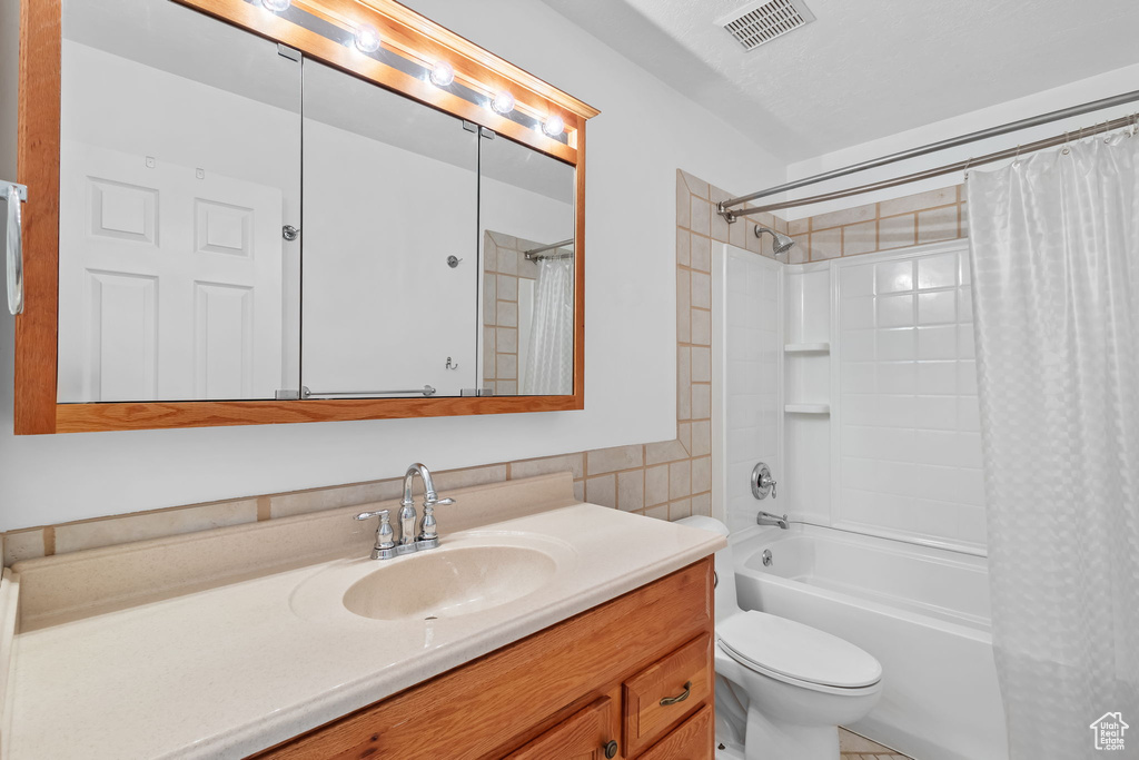 Full bath with tile walls, vanity, shower / bath combination with curtain, toilet, and visible vents