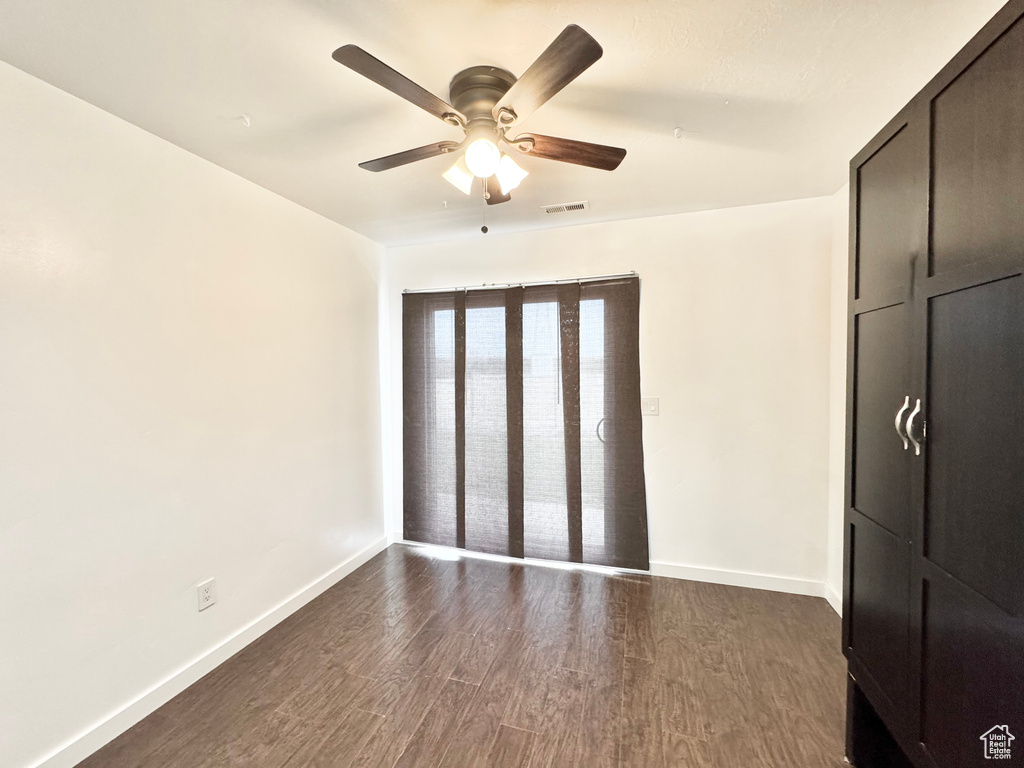 Unfurnished bedroom featuring visible vents, a ceiling fan, dark wood-style floors, and baseboards
