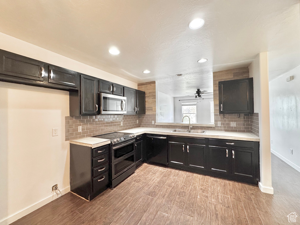 Kitchen featuring appliances with stainless steel finishes, light countertops, light wood-style flooring, and a sink