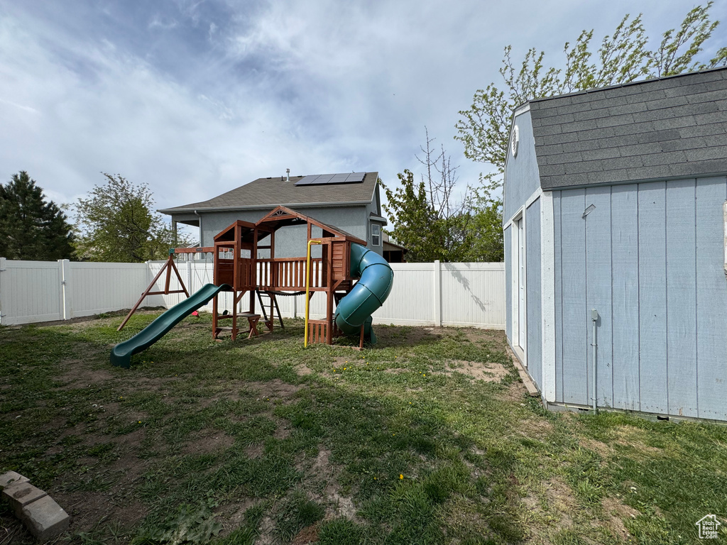 View of play area with a lawn, a storage shed, an outbuilding, and a fenced backyard
