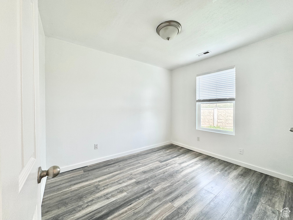 Unfurnished room with baseboards, visible vents, and wood finished floors