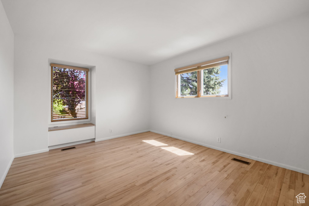 Spare room with visible vents, light wood finished floors, and baseboards