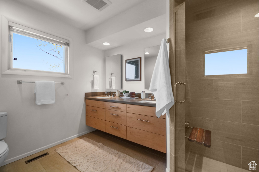 Bathroom featuring toilet, a sink, visible vents, and a stall shower
