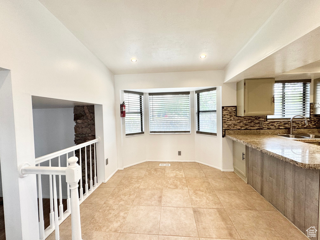 Kitchen featuring light tile patterned floors, tasteful backsplash, a sink, light stone countertops, and recessed lighting