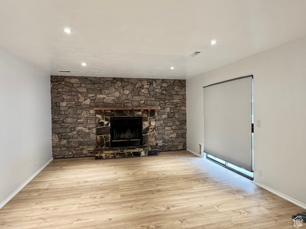 Unfurnished living room with recessed lighting, a stone fireplace, wood finished floors, and baseboards