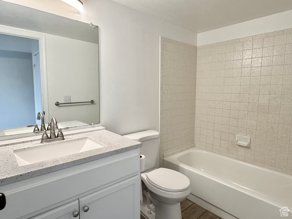 Bathroom with toilet, wood finished floors, vanity, and  shower combination