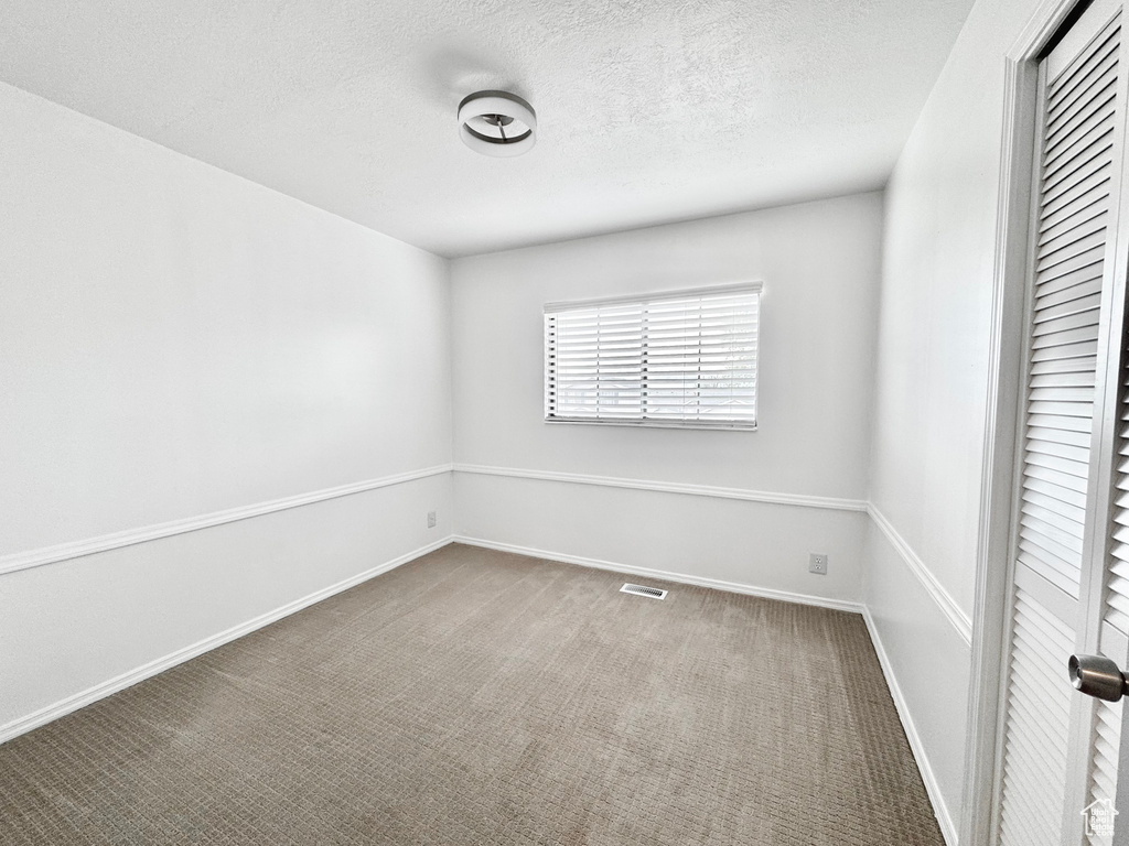 Unfurnished bedroom with a closet, visible vents, baseboards, a textured ceiling, and carpet floors