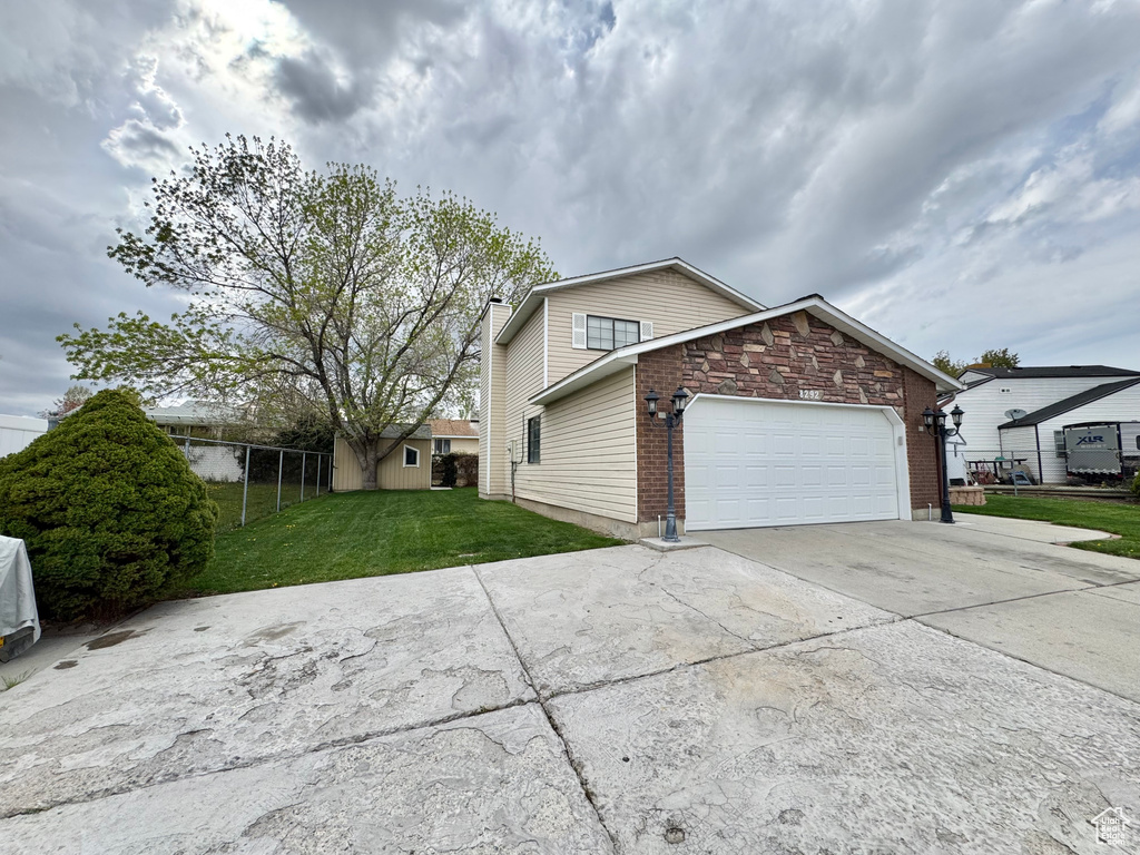 View of property exterior featuring a chimney, fence, a garage, concrete driveway, and a lawn