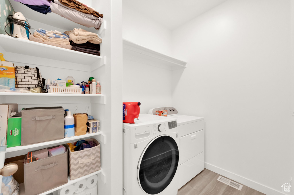 Laundry room with laundry area, light wood finished floors, separate washer and dryer, baseboards, and visible vents