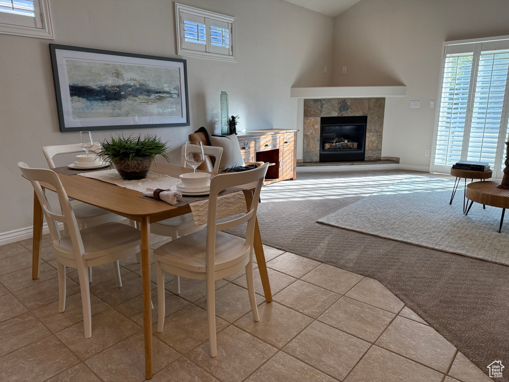 Dining space with a tile fireplace, baseboards, and light carpet