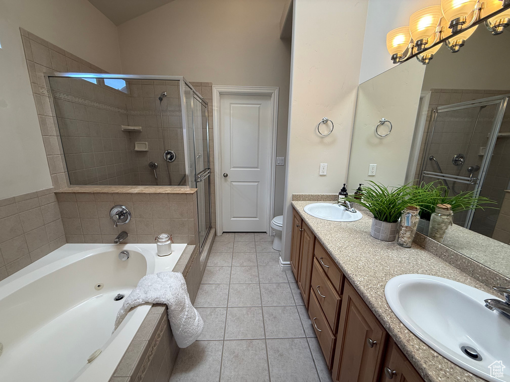 Bathroom featuring double vanity, a stall shower, a whirlpool tub, a chandelier, and tile patterned flooring