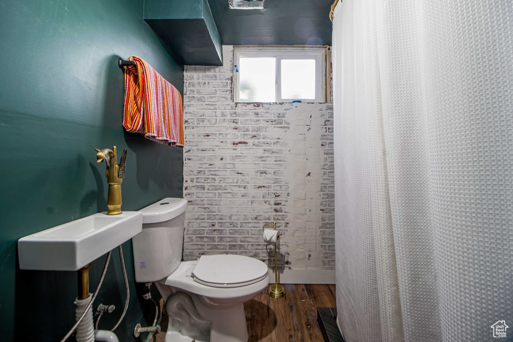Full bath with toilet, curtained shower, and wood finished floors