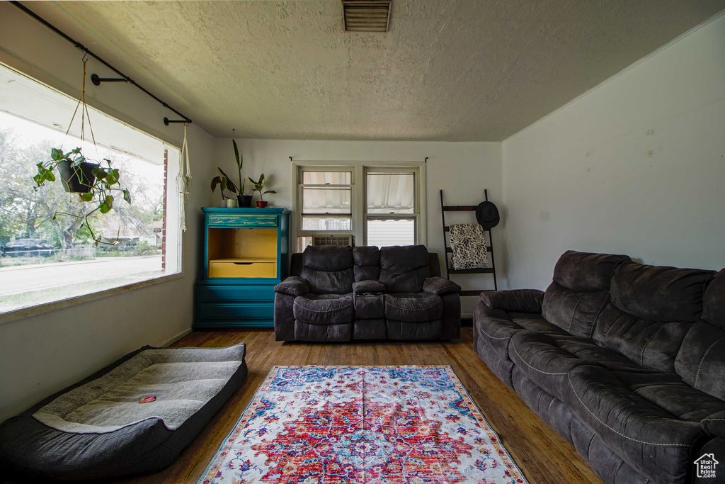 Living area featuring visible vents, wood finished floors, and a textured ceiling