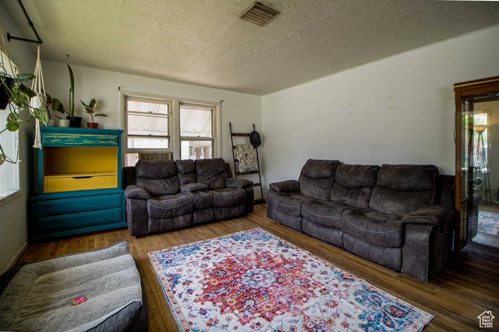 Living room featuring a textured ceiling, visible vents, and wood finished floors