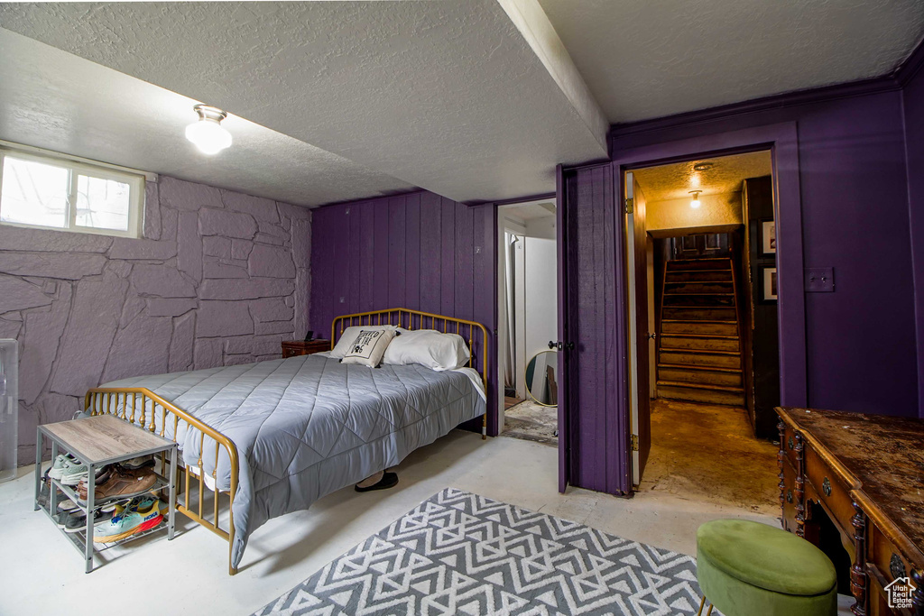Bedroom with wooden walls, a textured ceiling, and concrete floors
