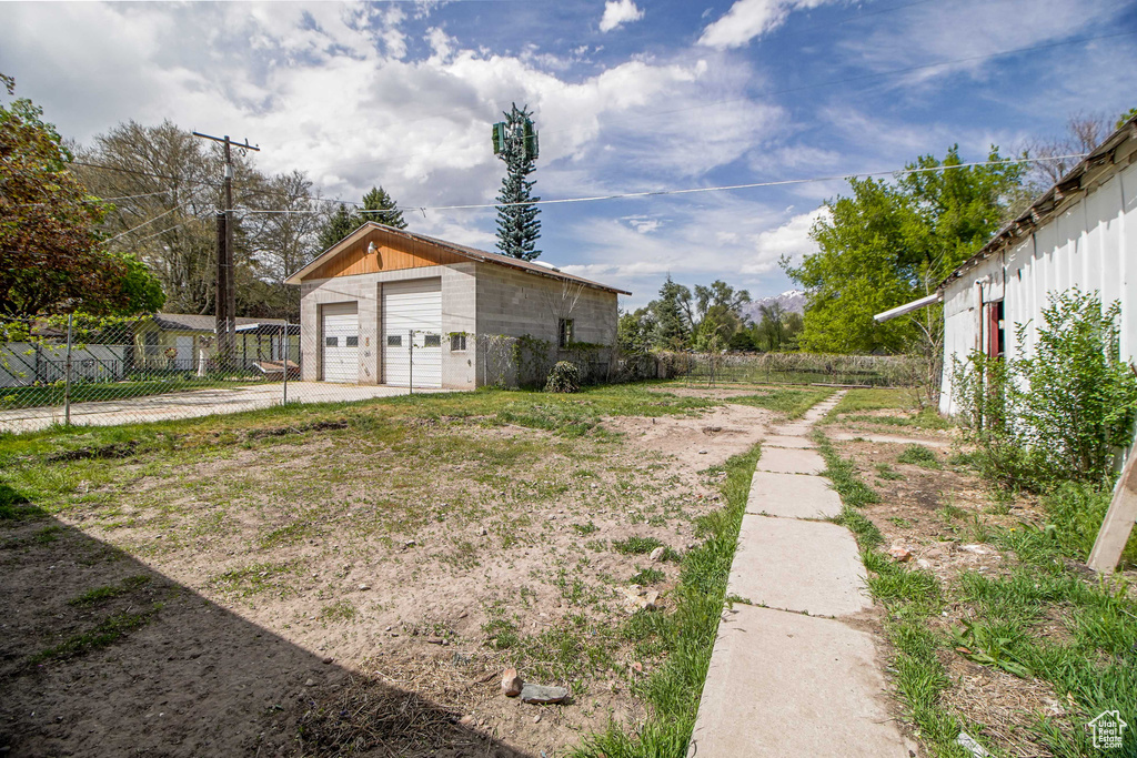 View of yard featuring an outbuilding, a detached garage, and fence