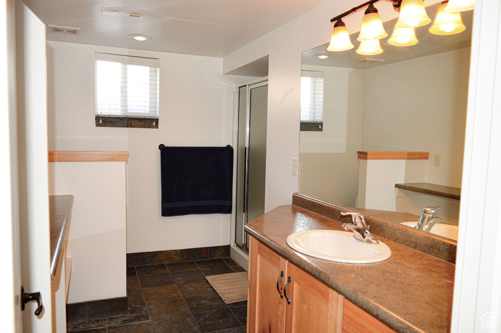 Full bathroom with a shower stall, a chandelier, vanity, visible vents, and baseboards