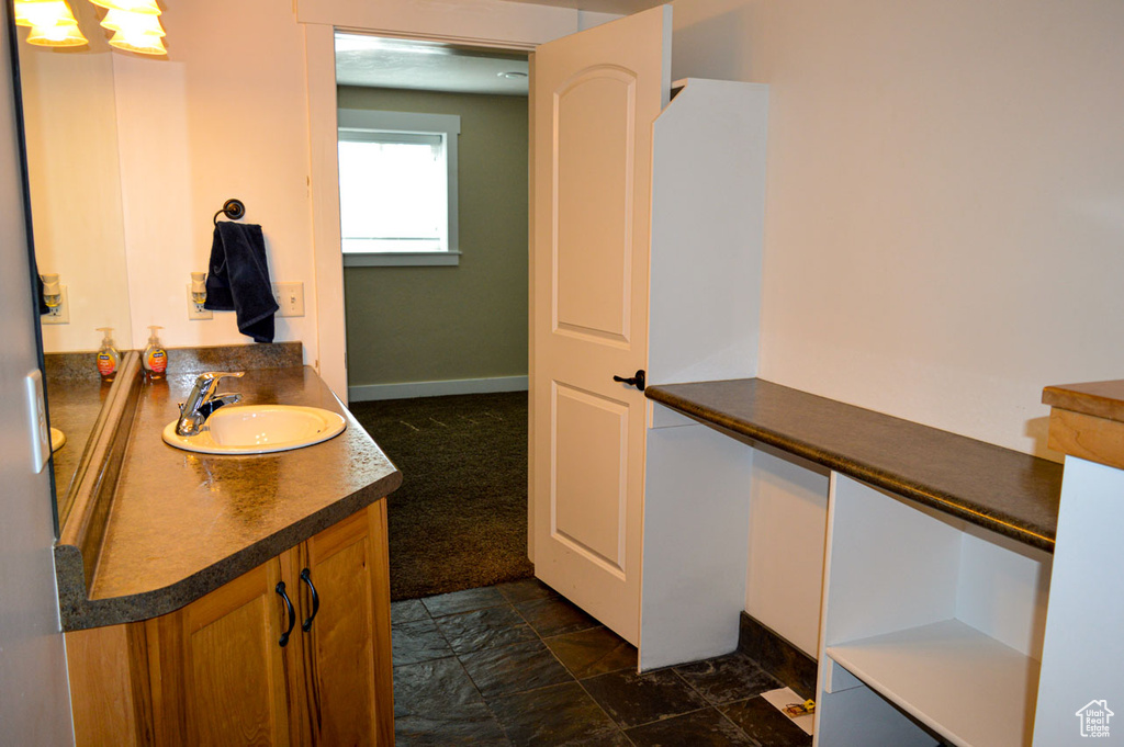 Bathroom featuring stone finish floor, vanity, and baseboards
