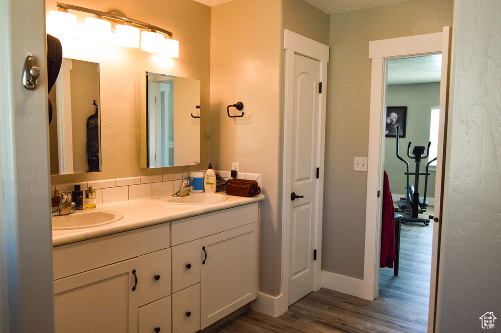Bathroom with double vanity, wood finished floors, baseboards, and a sink