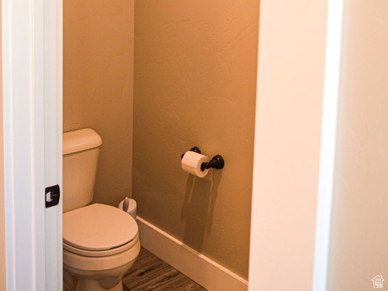 Bathroom featuring baseboards, wood finished floors, and toilet