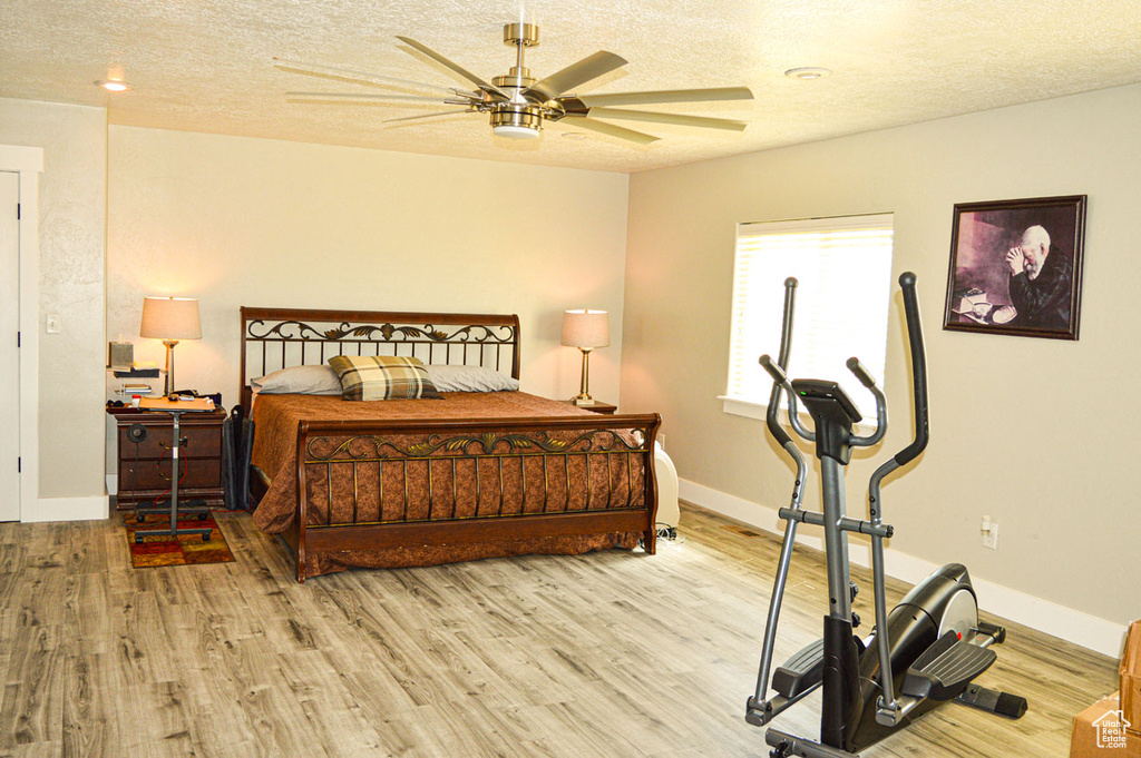Bedroom featuring a textured ceiling, a ceiling fan, baseboards, and light wood-style floors