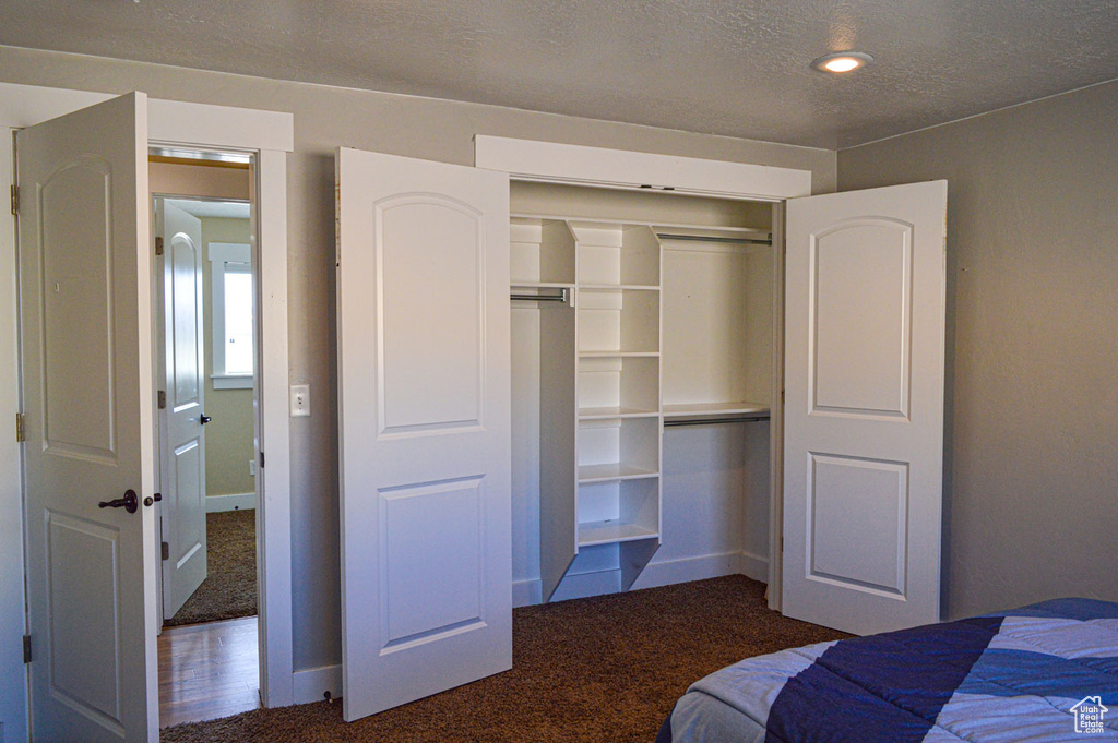 Unfurnished bedroom with carpet, baseboards, a textured ceiling, and a closet