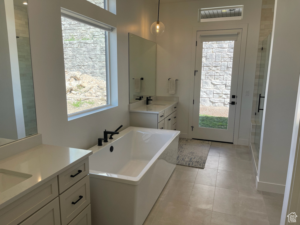 Bathroom featuring a sink, a stall shower, two vanities, a freestanding bath, and tile patterned flooring