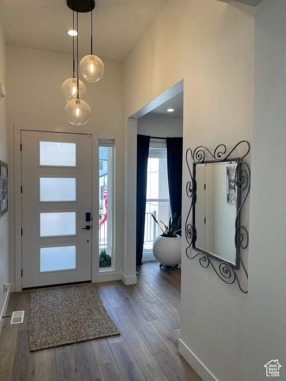 Foyer entrance with wood finished floors, visible vents, a high ceiling, and baseboards