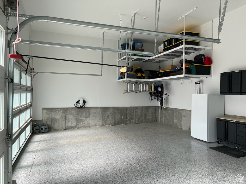 Garage with a garage door opener and freestanding refrigerator
