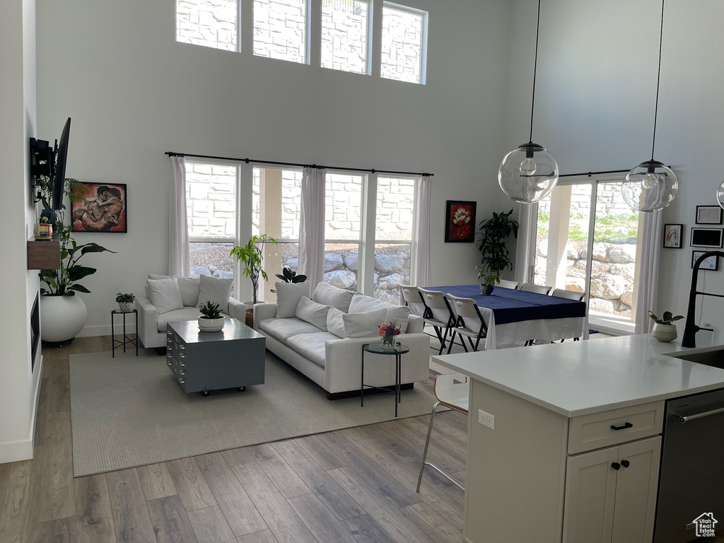 Living room featuring a high ceiling, baseboards, and light wood-type flooring