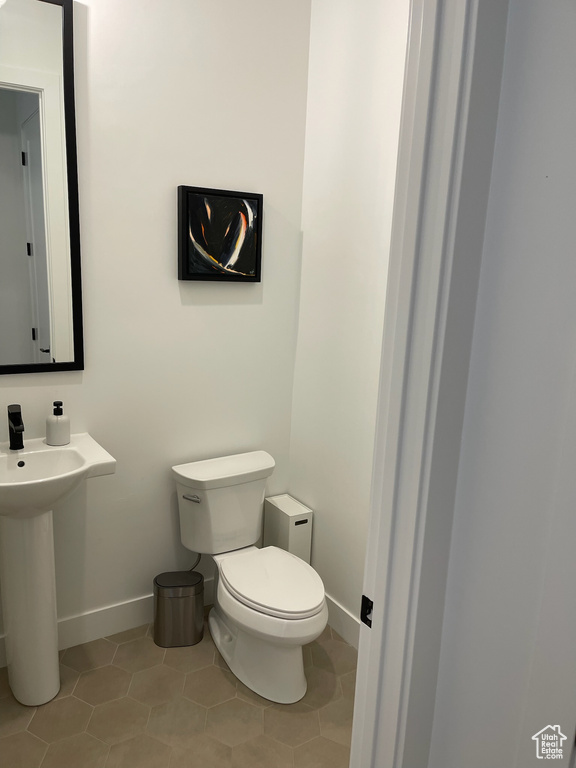 Half bath featuring toilet, tile patterned flooring, and baseboards