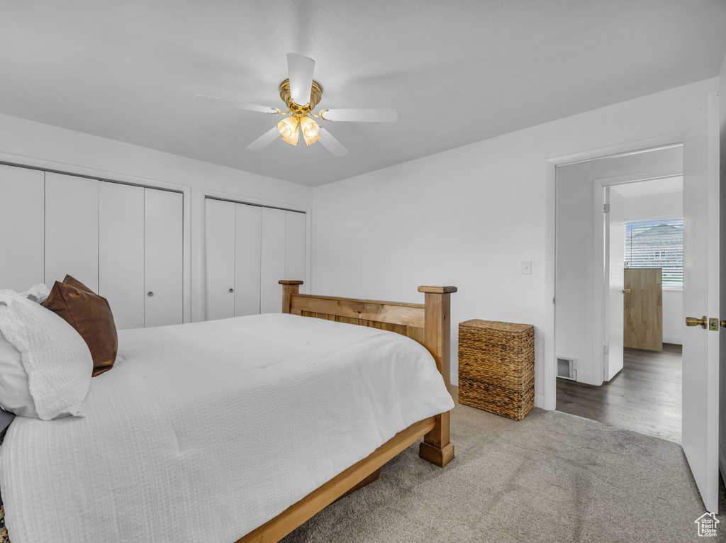 Carpeted bedroom featuring visible vents, a ceiling fan, and two closets