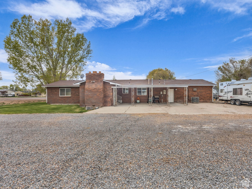 Back of property featuring a patio, a chimney, and brick siding