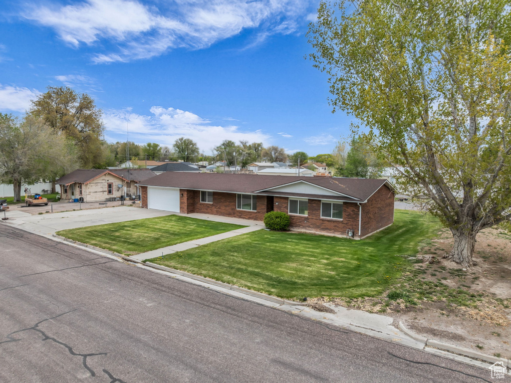 Single story home with an attached garage, a front lawn, brick siding, and concrete driveway