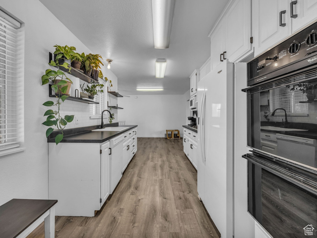 Kitchen with decorative backsplash, dark countertops, open shelves, a sink, and white cabinets