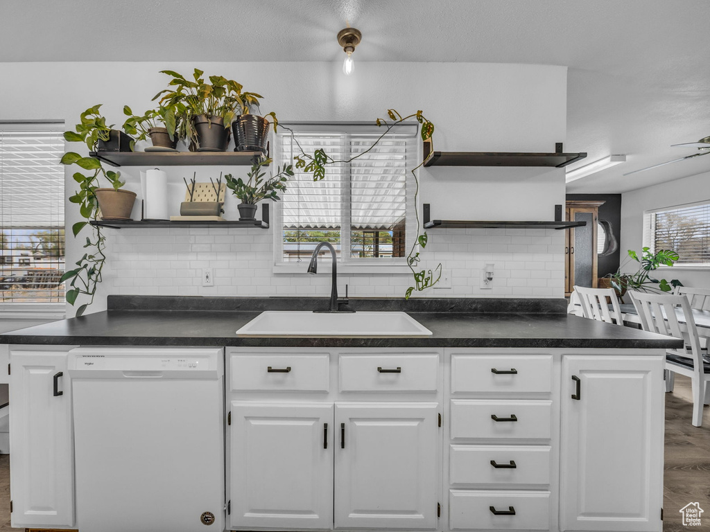 Kitchen featuring white dishwasher, open shelves, a sink, and wood finished floors