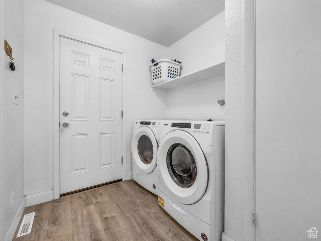 Washroom featuring laundry area, visible vents, wood finished floors, washer and dryer, and baseboards