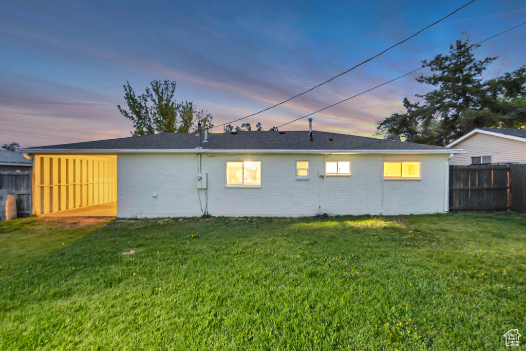 Back of property with a yard, brick siding, and fence